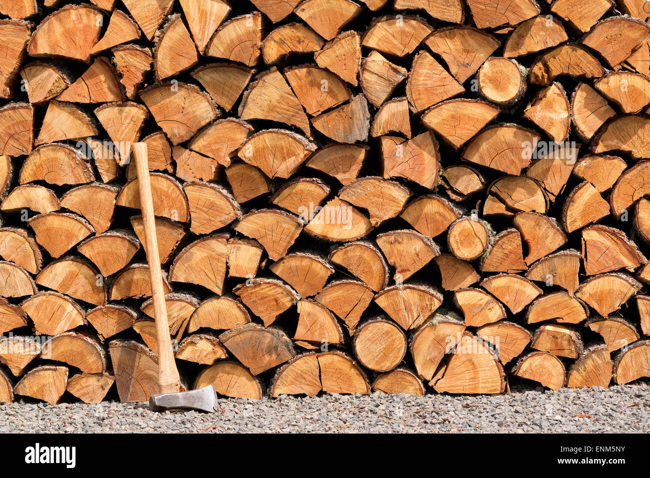 Splitting maul and neatly stacked pile of split firewood. Stock Photo