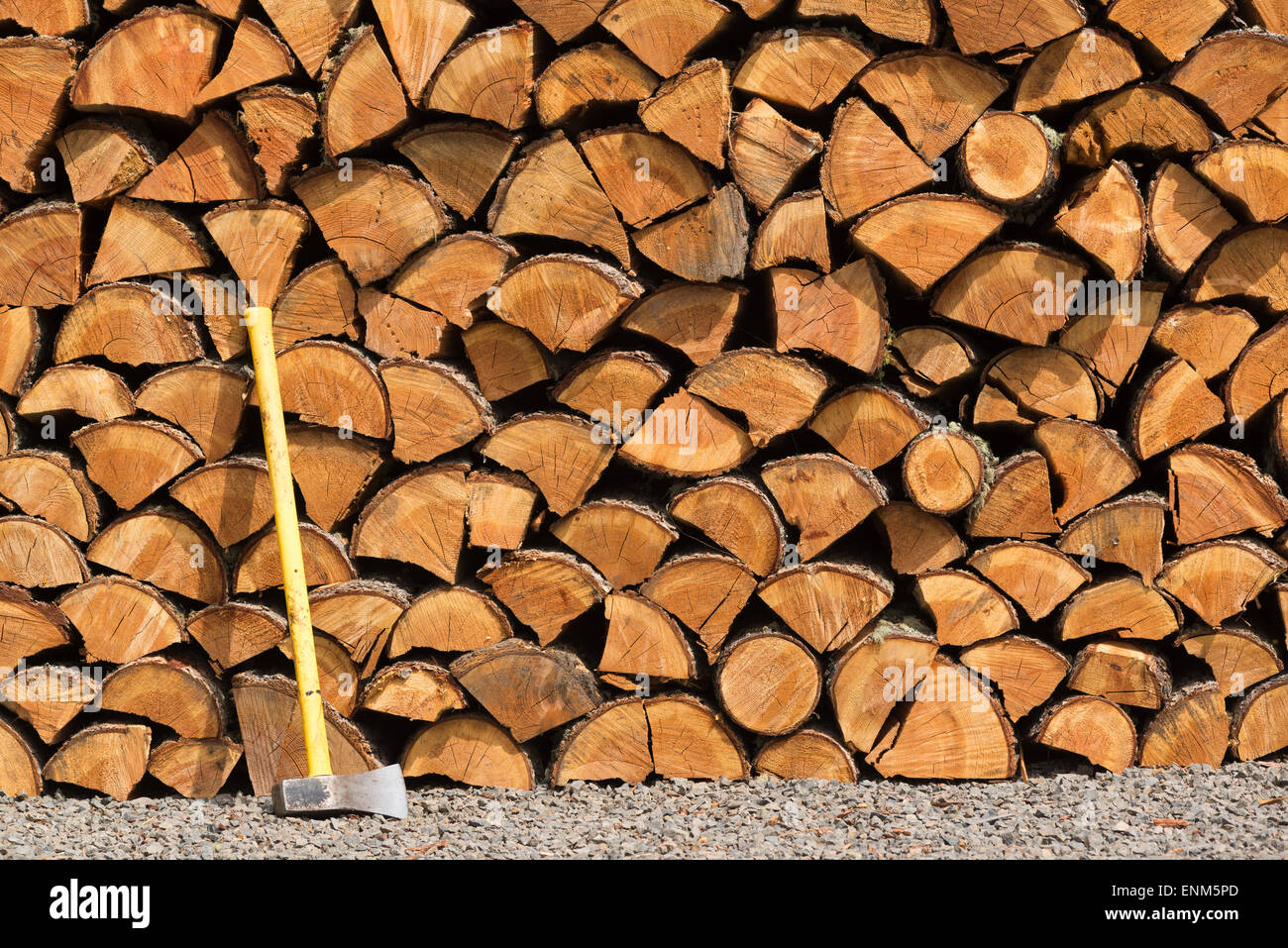 Splitting maul and neatly stacked pile of split firewood. Stock Photo