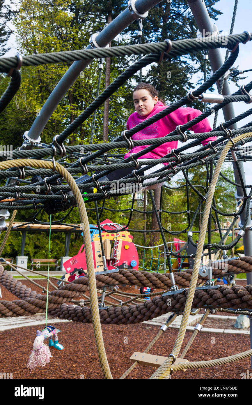 Young girl resting on the rope mesh of a climbing frame in Vancouver