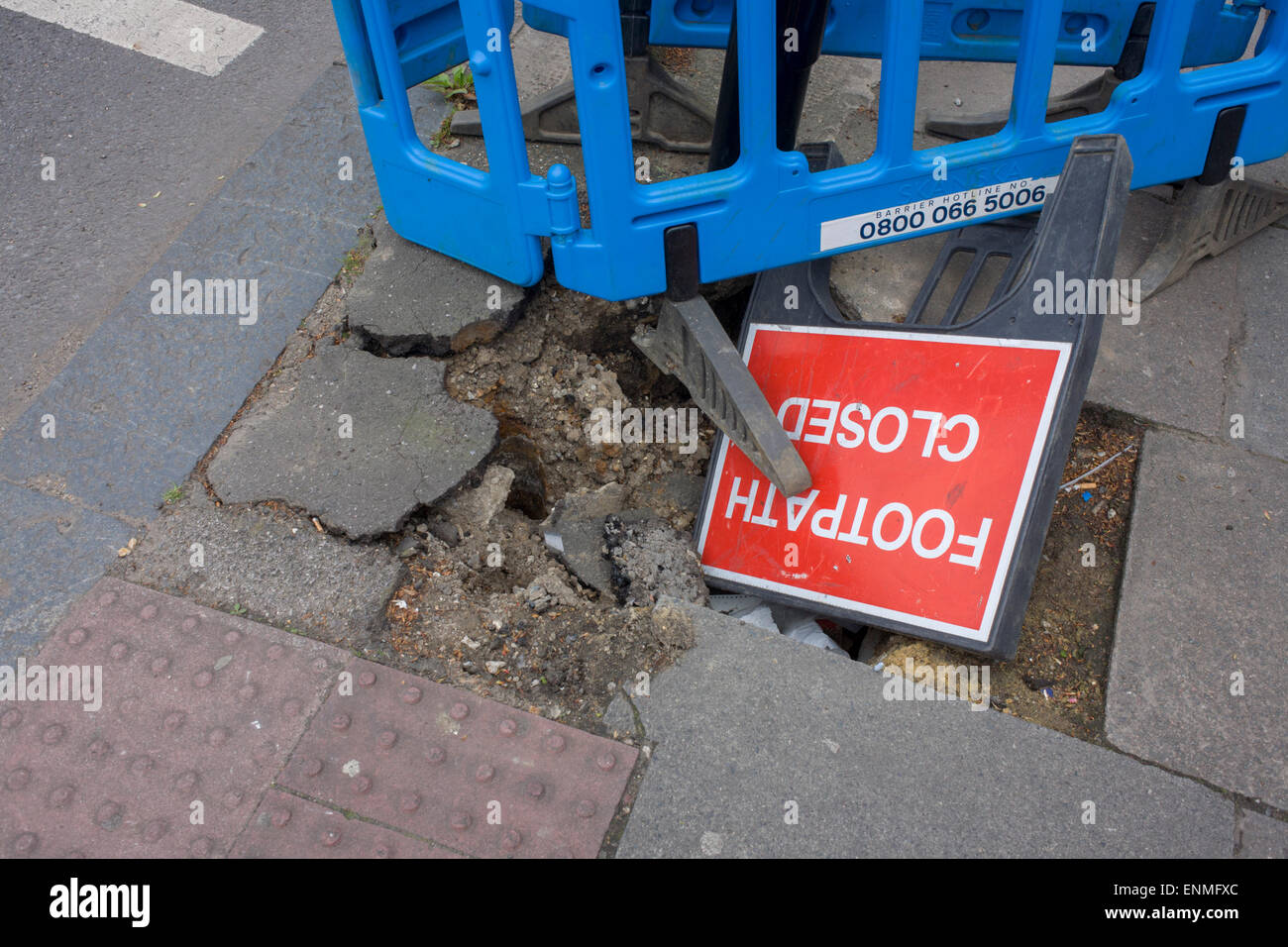 A Closed Footpath sign fallen into a hole during pavement works in the