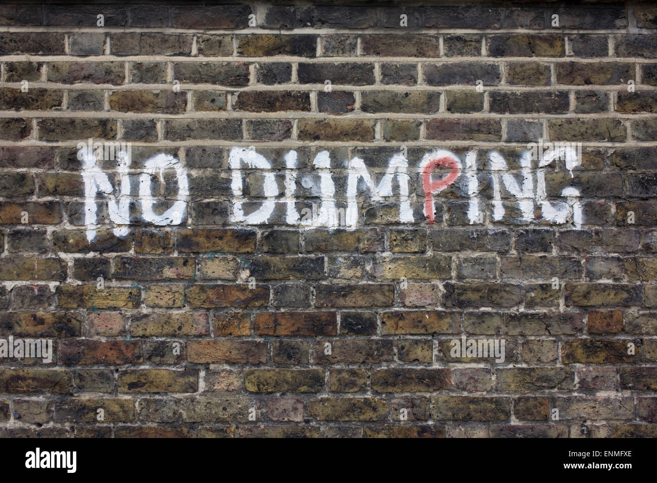 No Dumping writing painted on an urban brick wall in the south London borough of Lewisham, SE5. Stock Photo
