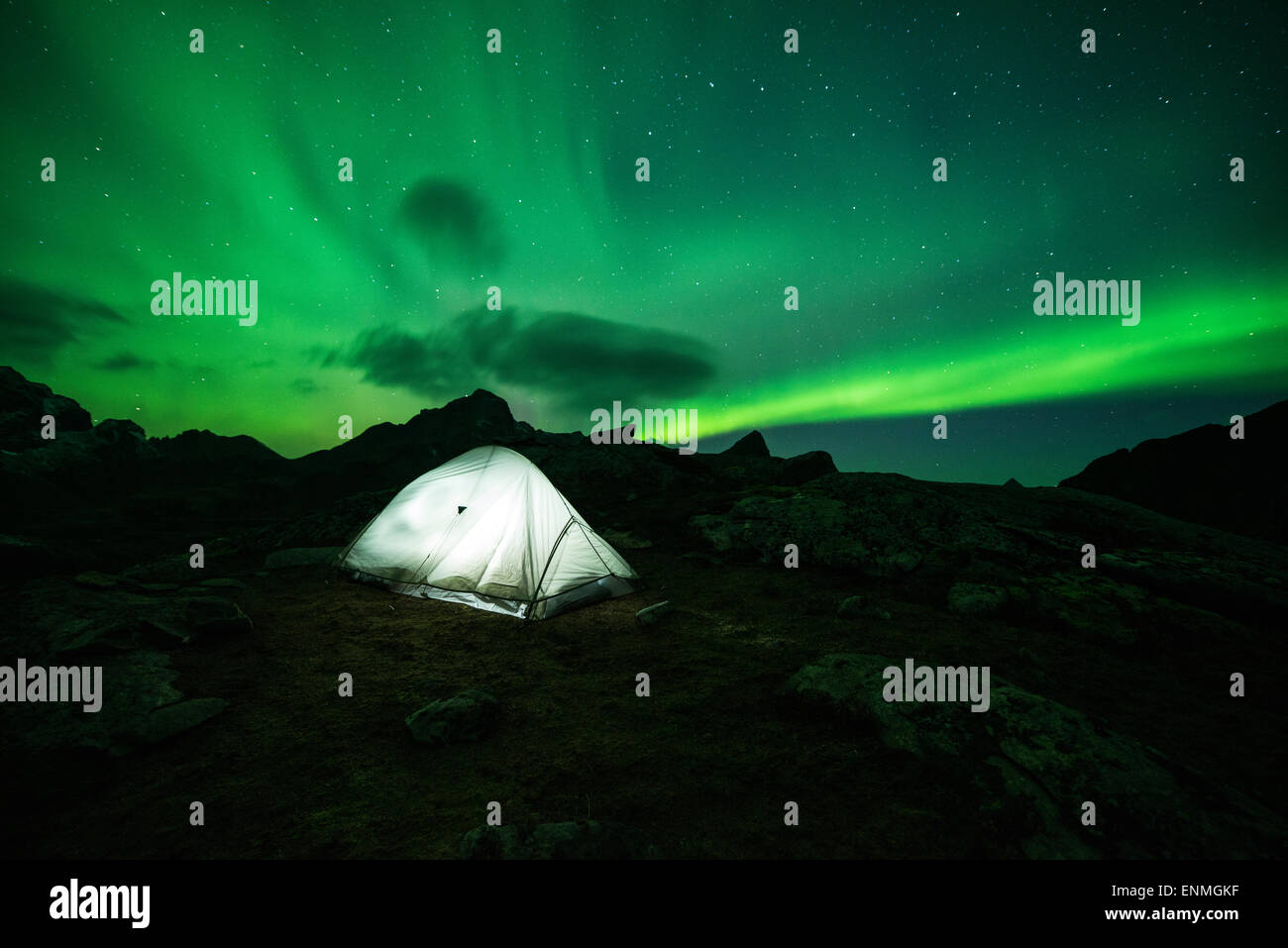 Northern Lights - Aurora Borealis fill sky over tent and mountains, Moskenesøy, Lofoten Islands, Norway Stock Photo