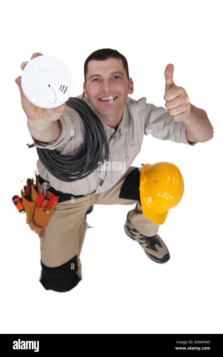 Tradesman holding up a smoke detector Stock Photo