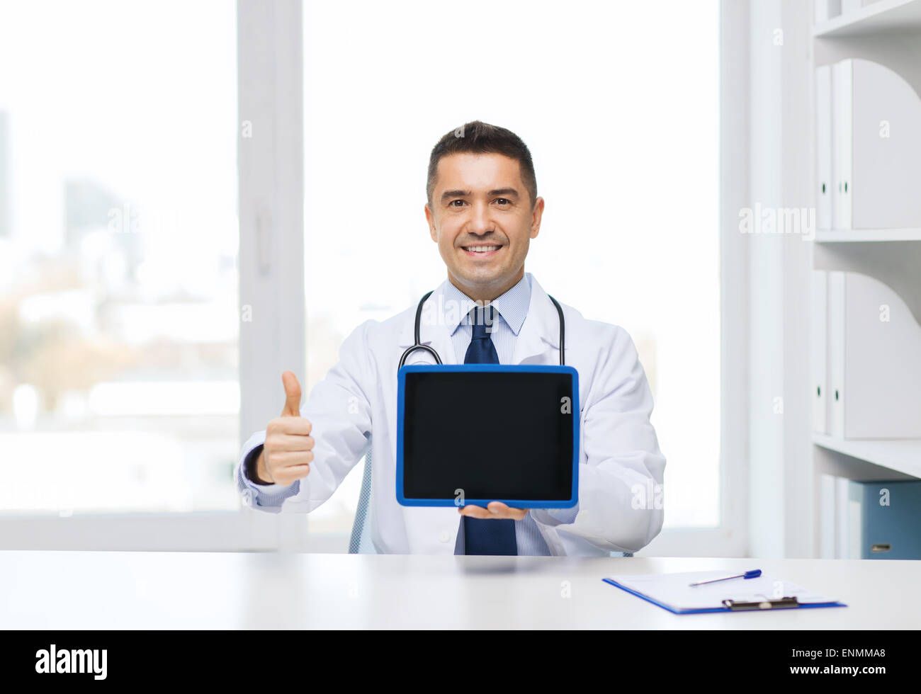 smiling doctor showing tablet pc and thumbs up Stock Photo - Alamy