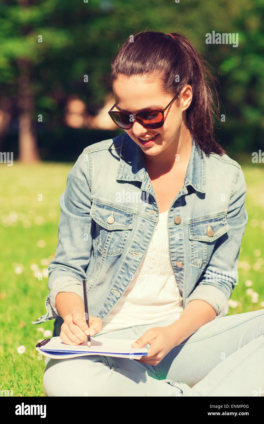 smiling young girl with notebook writing in park Stock Photo - Alamy
