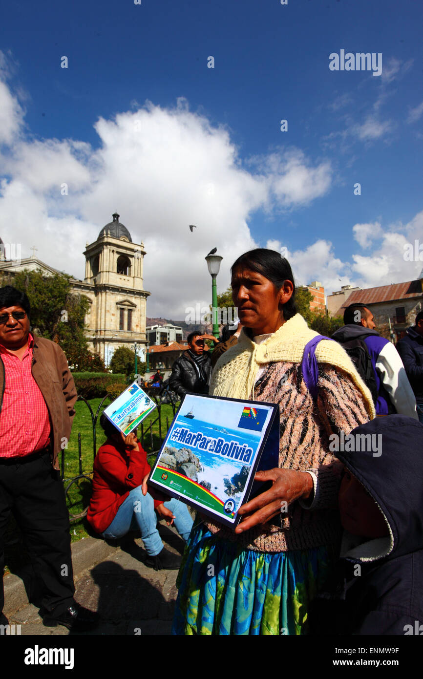 La Paz, Bolivia, 8th May 2015. An Aymara woman holds a banner with the hashtag #MarParaBolivia (Sea for Bolivia) while watching Bolivia's final presentation to the International Court of Justice in The Hague on a giant screen in Plaza Murillo. The initial hearings for Bolivia's case reclaiming access to the Pacific Ocean against Chile have been taking place in the ICJ this week, the hearings were to debate the Chilean objection that the court doesn't have the jurisdiction to judge the case. Credit:  James Brunker / Alamy Live News Stock Photo