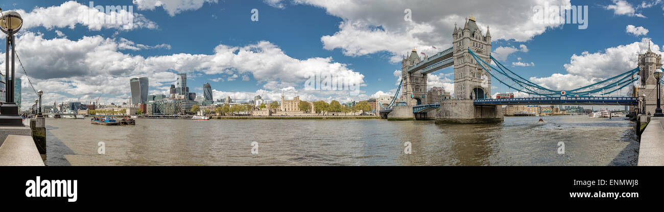 Panorama of Tower Bridge, the Tower of London and the city with the river Thames in foreground with blue skies and fluffy clouds Stock Photo