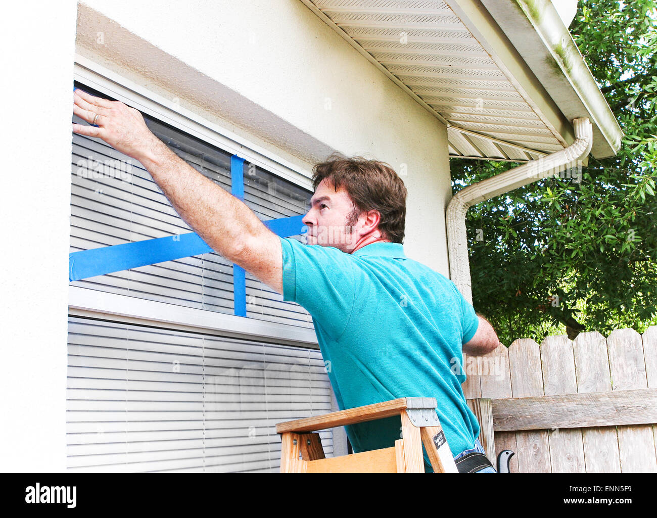 Man taping the windows on his home to protect from broken glass in a hurricane Stock Photo Alamy