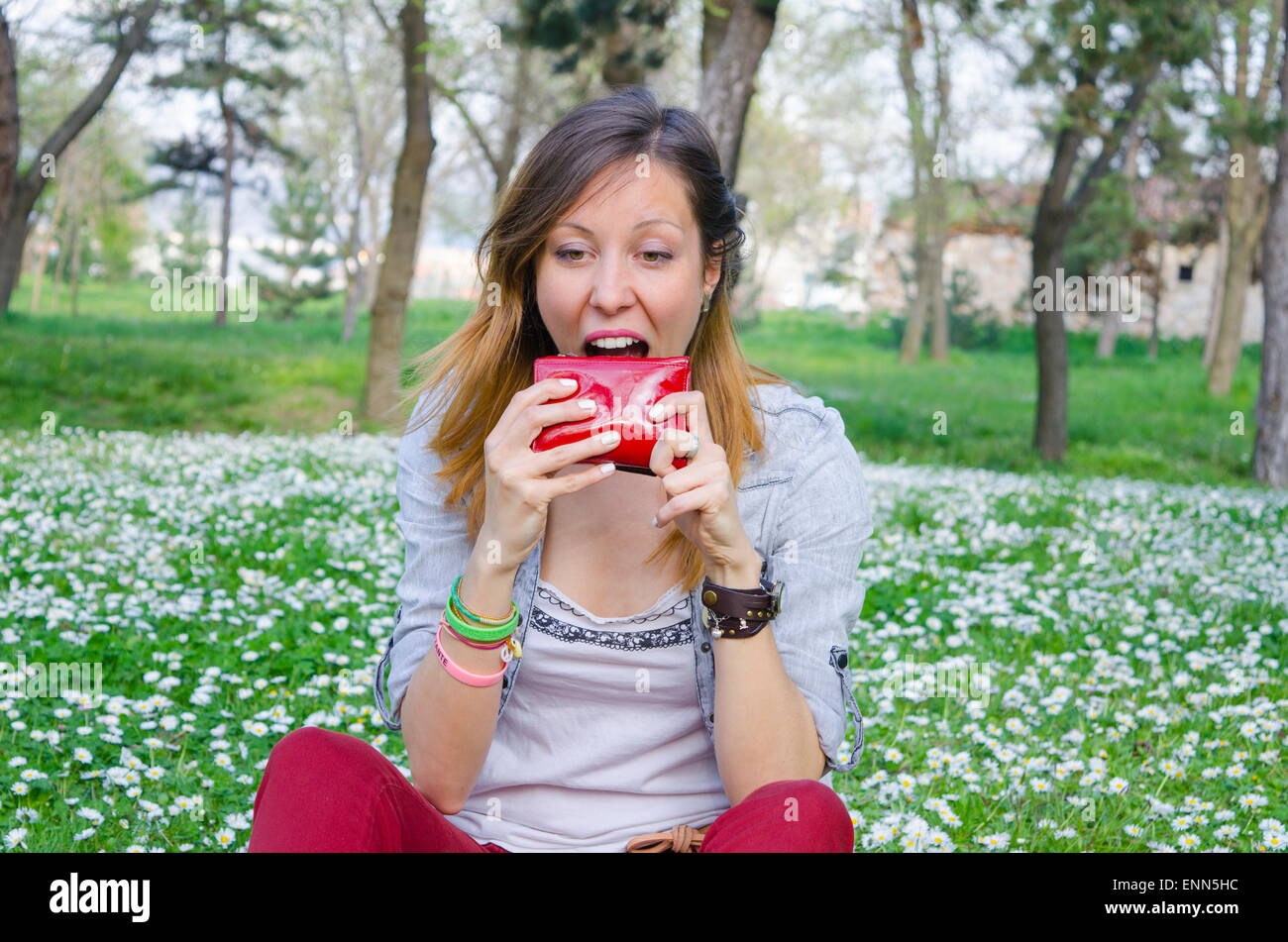 Brunette broke in spring trying to eat her wallet among the daisies Stock Photo