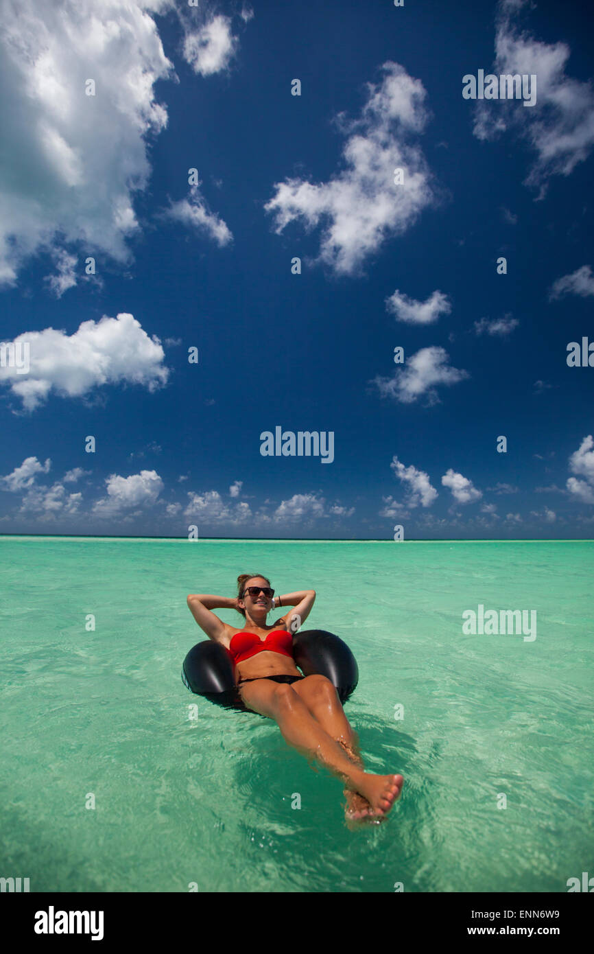 A young woman relaxes on an inflatable tire in turquoise water while on vacation in Cayo Coco, Cuba. Stock Photo