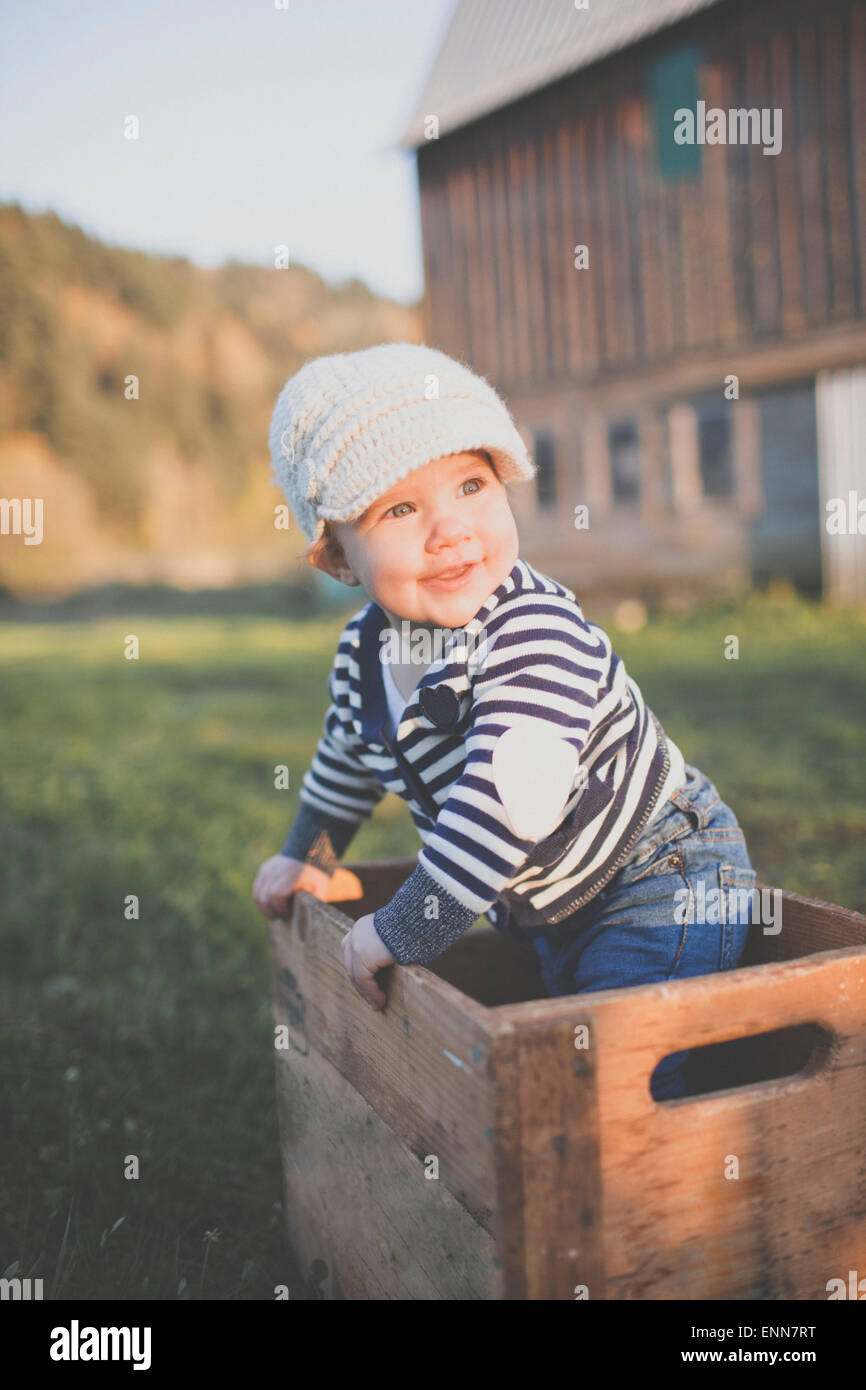 Portrait of a baby standing up inside an old wooden crate. Stock Photo