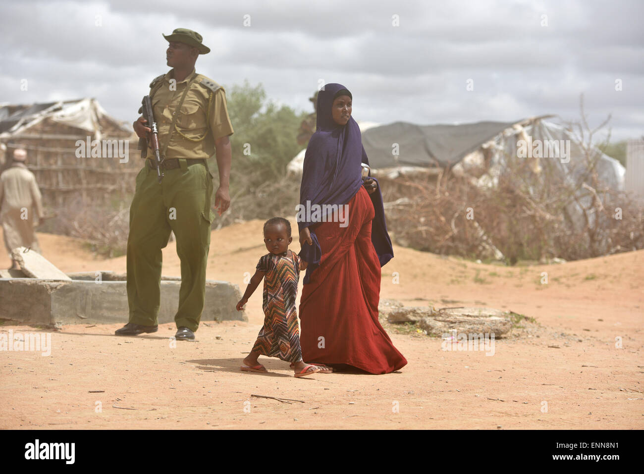 (150508) --DADAAB, May 8, 2015 (Xinhua) -- A refugee mother and her child walk past an armed police at Dadaab refugee camp in Kenya, May 8, 2015. Dadaab, the world's largest refugee camp in northeastern Kenya, currently houses some 350,000 people. For more than 20 years, it has been home to generations of Somalis who have fled their homeland wracked by conflicts. (Xinhua/Sun Ruibo) Stock Photo