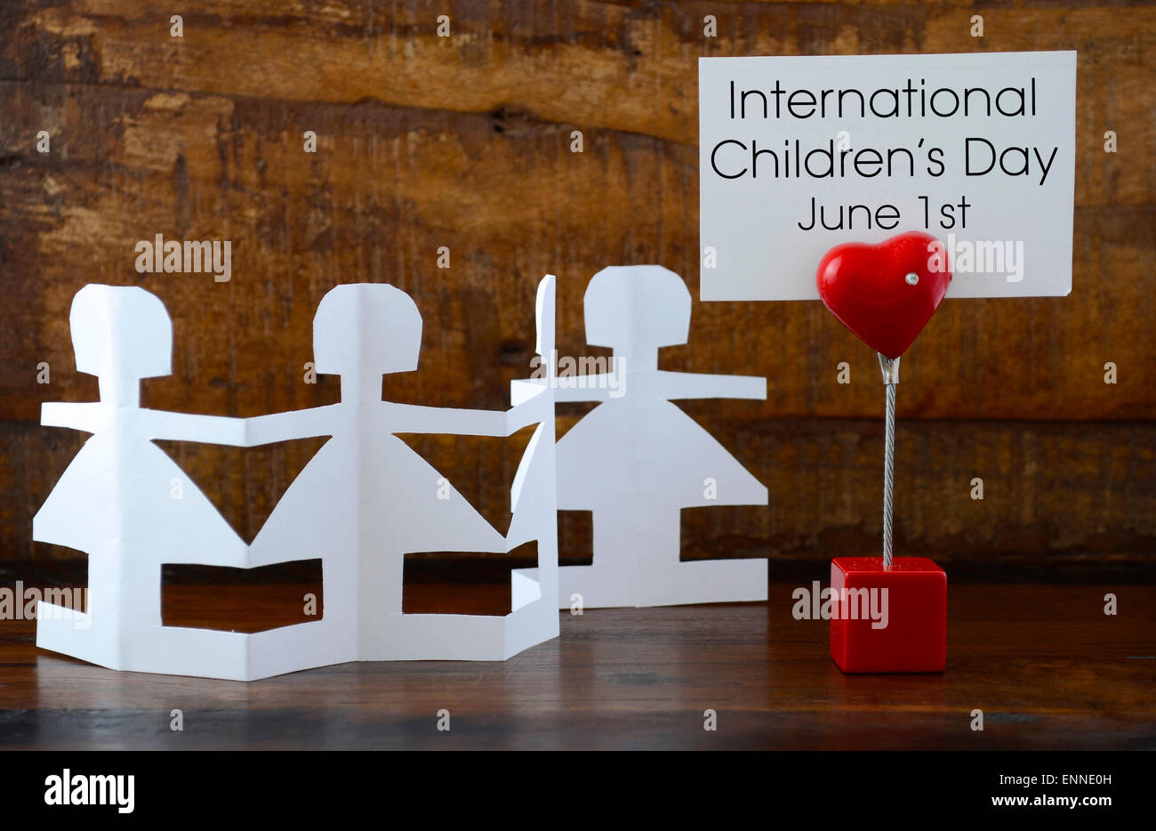 International Childrens Day concept with paper dolls on dark wood background, with message on red heart sign. Stock Photo