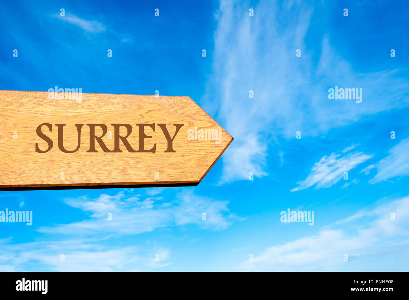 Wooden arrow sign pointing destination SURREY, ENGLAND against clear blue sky with copy space available. Travel destination conceptual image Stock Photo