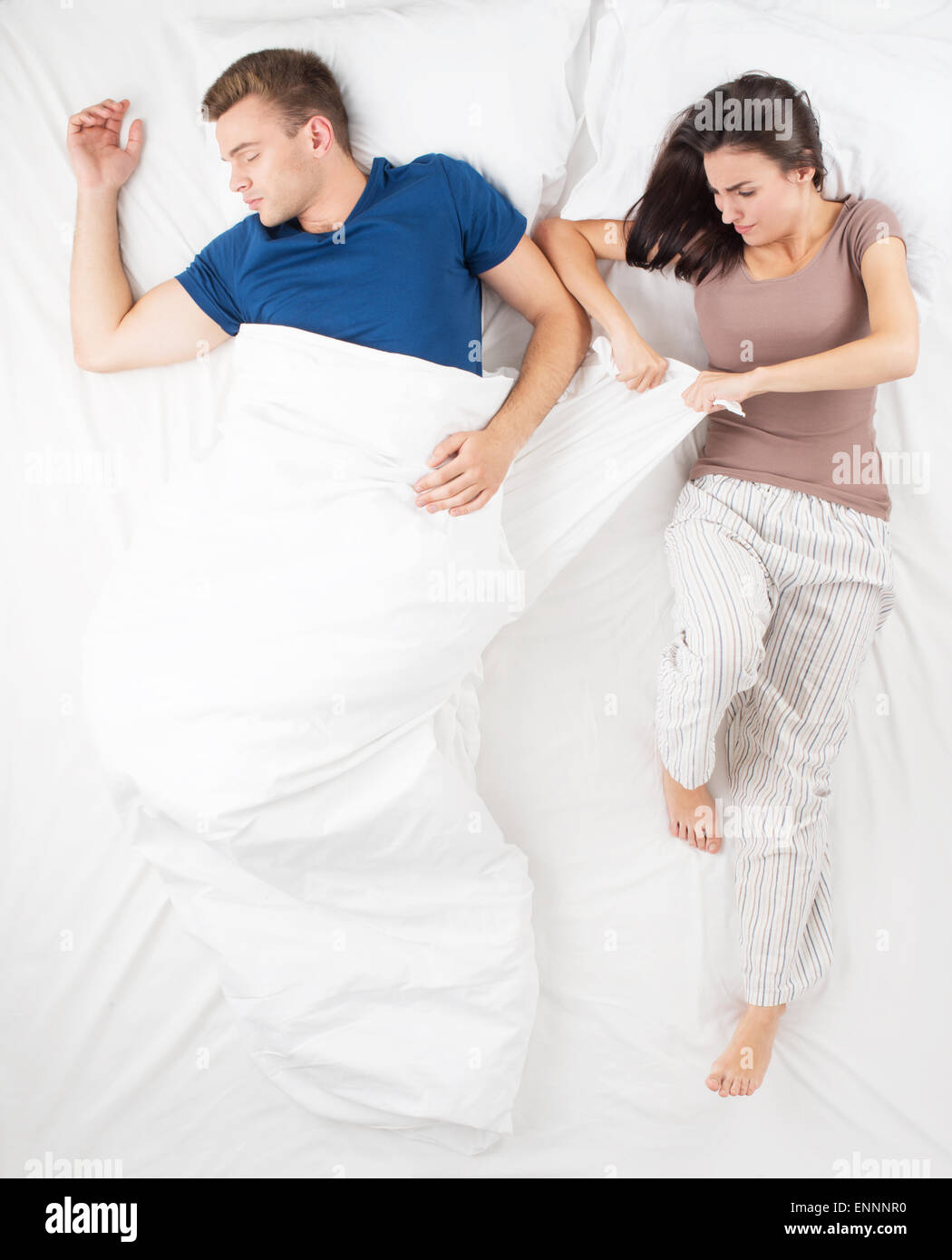 Young couple dividing a blanket while sleeping Stock Photo