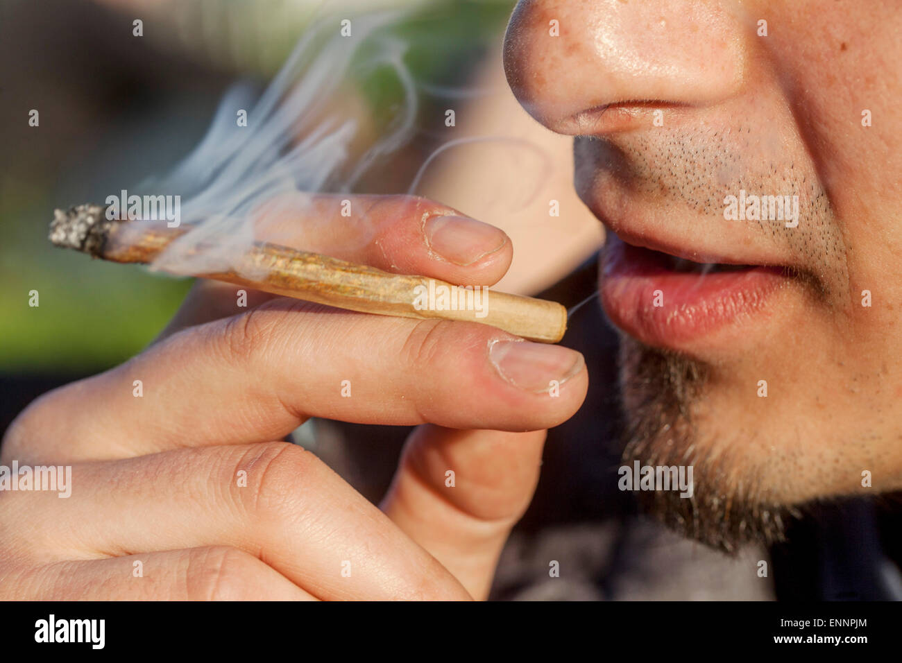Close up young man smoking marijuana joint Stock Photo