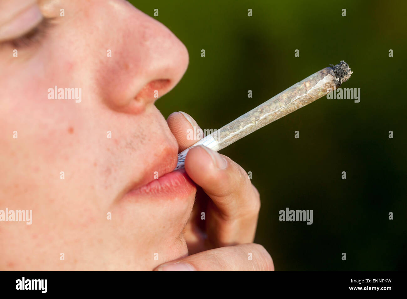 Close up Teenager smoking marijuana joint Young man Smoking joint Man Smoking marijuana cigarette Joint Male Teenage Boy inhaling Cannabis joint Face Stock Photo
