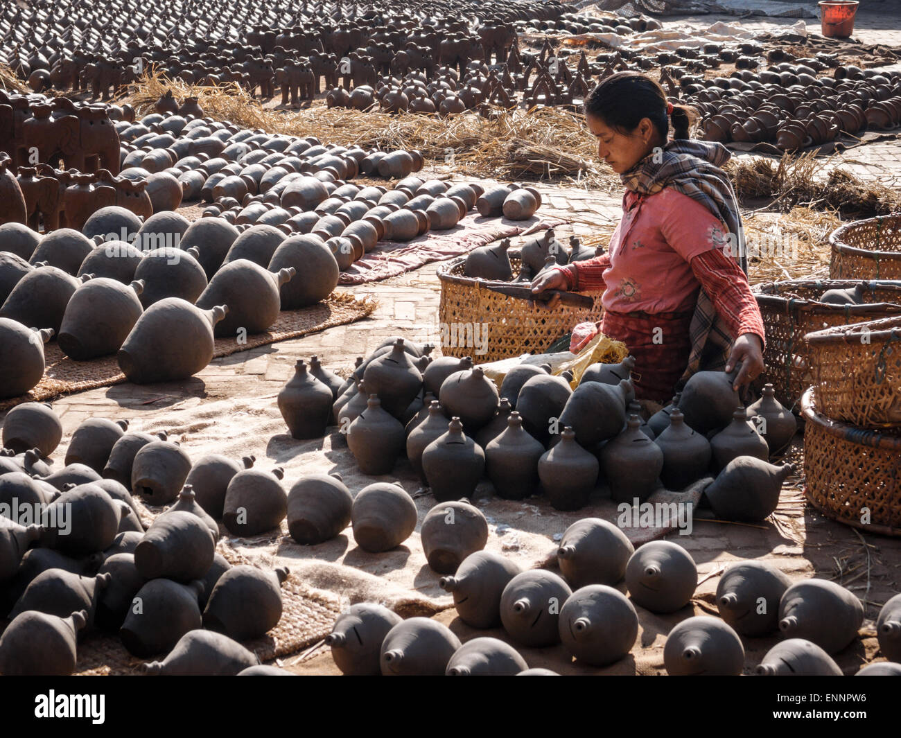 Woman laying out clay money jars to dry in the sun in Potter's Square in Bhaktapur, Nepal Stock Photo