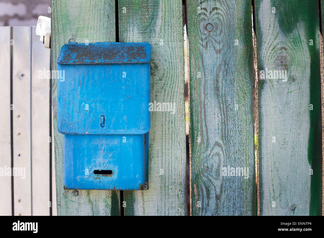Blue mailbox attached to old green fence Stock Photo
