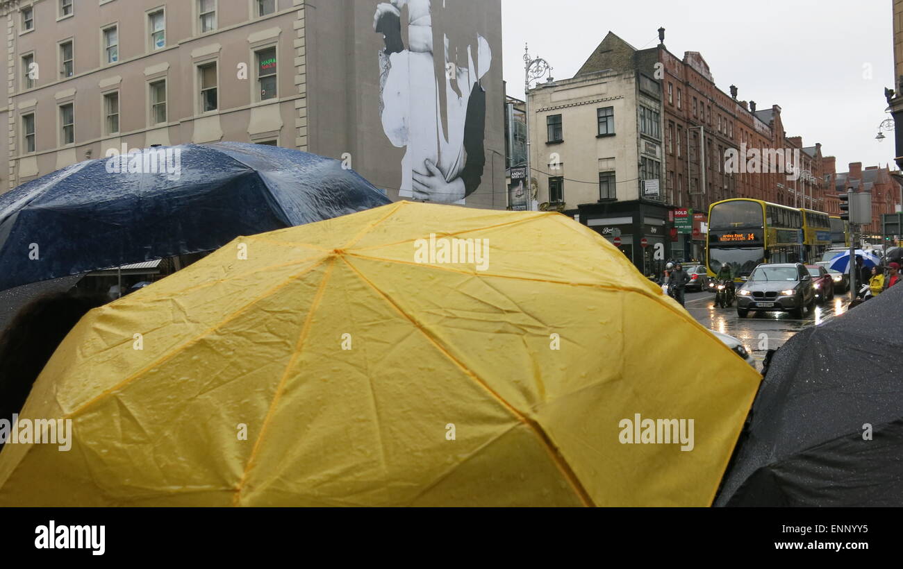 People hold up umbrellas while waiting at traffic lights in Dublin city
