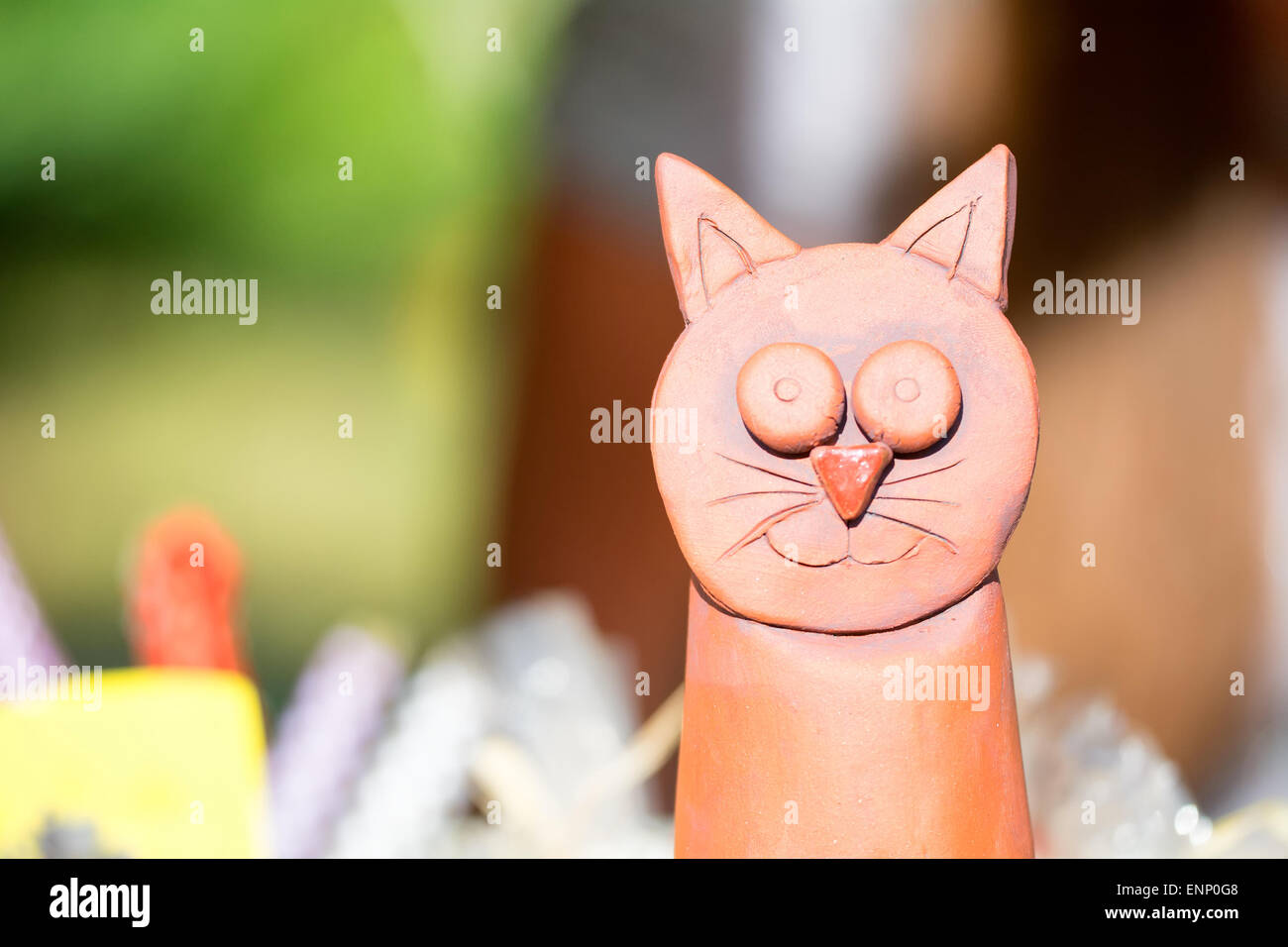 Detail of red ceramic cat with blurred background. Stock Photo