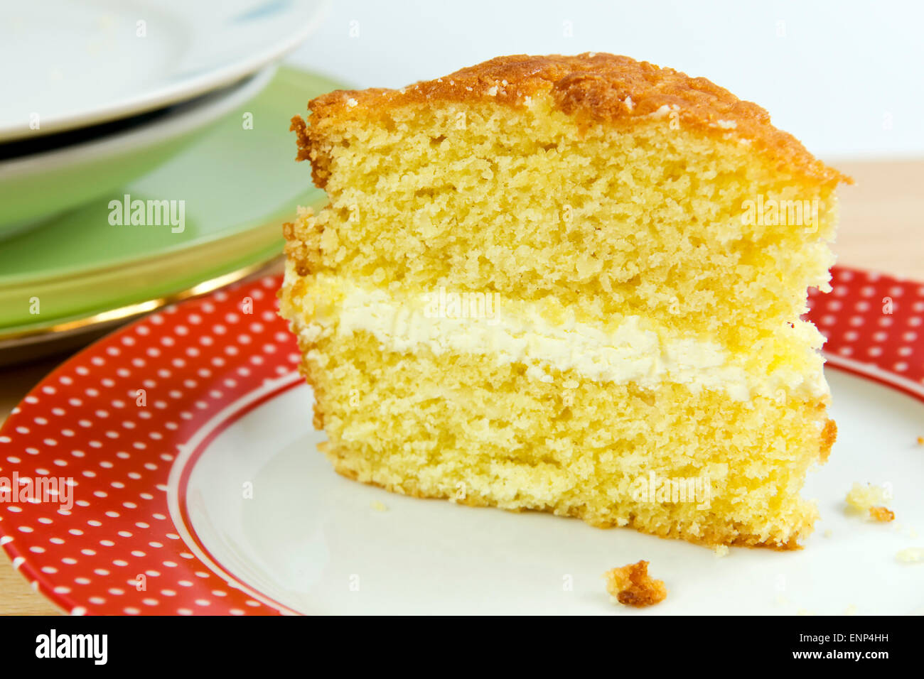 Sponge cake with a buttercream icing filling on red and white plate Stock Photo