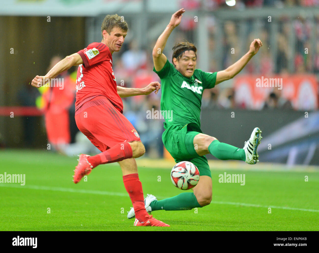 Munich, Germany. 9th May, 2015. Munich's Thomas Mueller and Augsburg's Jeong-Ho Hong compete for the ball during the German Bundesliga soccer match between Bayern Munich and FC Augsburg at the Allianz Arena in Munich, Germany, 9 May 2015. PHOTO: PETER KNEFFEL/dpa (EMBARGO CONDITIONS - ATTENTION - Due to the accreditation guidelines, the DFL only permits the publication and utilisation of up to 15 pictures per match on the internet and in online media during the match) Credit:  dpa/Alamy Live News Stock Photo