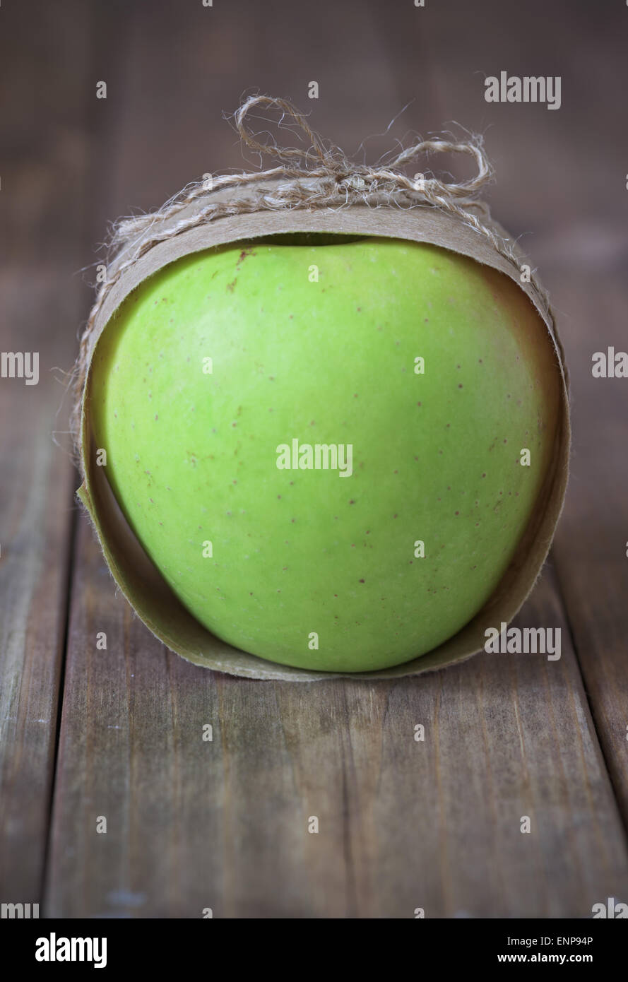 green apple wrapped in paper and tie a string on the wooden table Stock