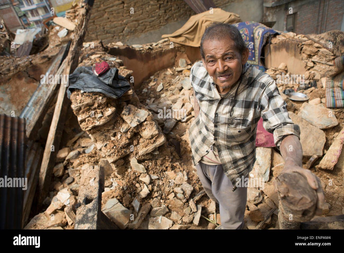 An elderly survivor of the 2015 earthquake stands in the rubble of his former home in Chautara town, Sindhulpalchowk District, Nepal. Stock Photo