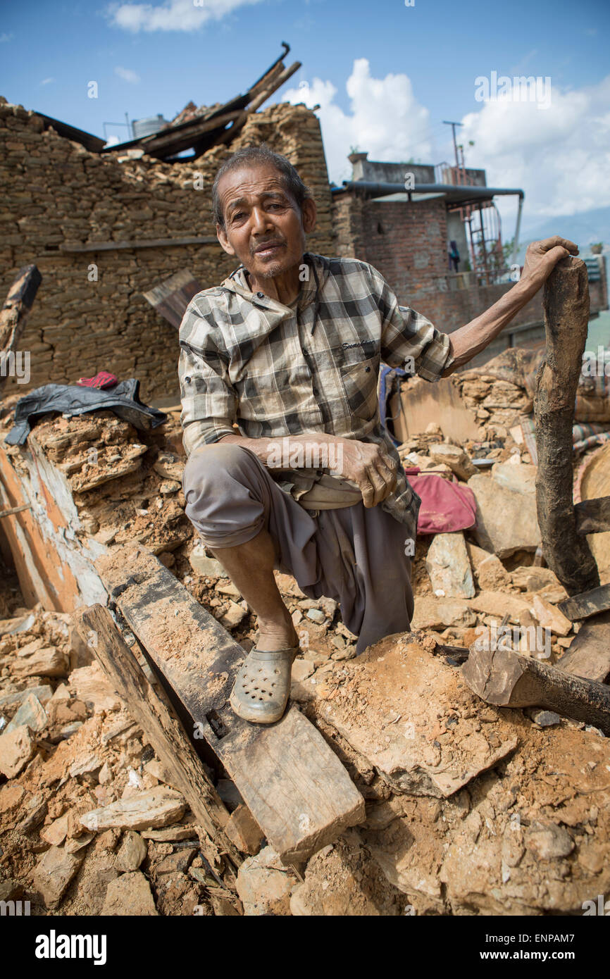 An elderly survivor of the 2015 earthquake stands in the rubble of his former home in Chautara town, Sindhulpalchowk District, Nepal. Stock Photo