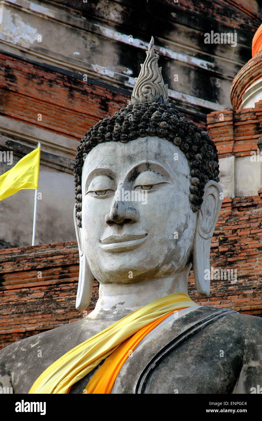 Ayutthaya, Thailand:  Face of a giant stone Buddha  with an enigmatic smile at the base of a giant Chedi Stock Photo