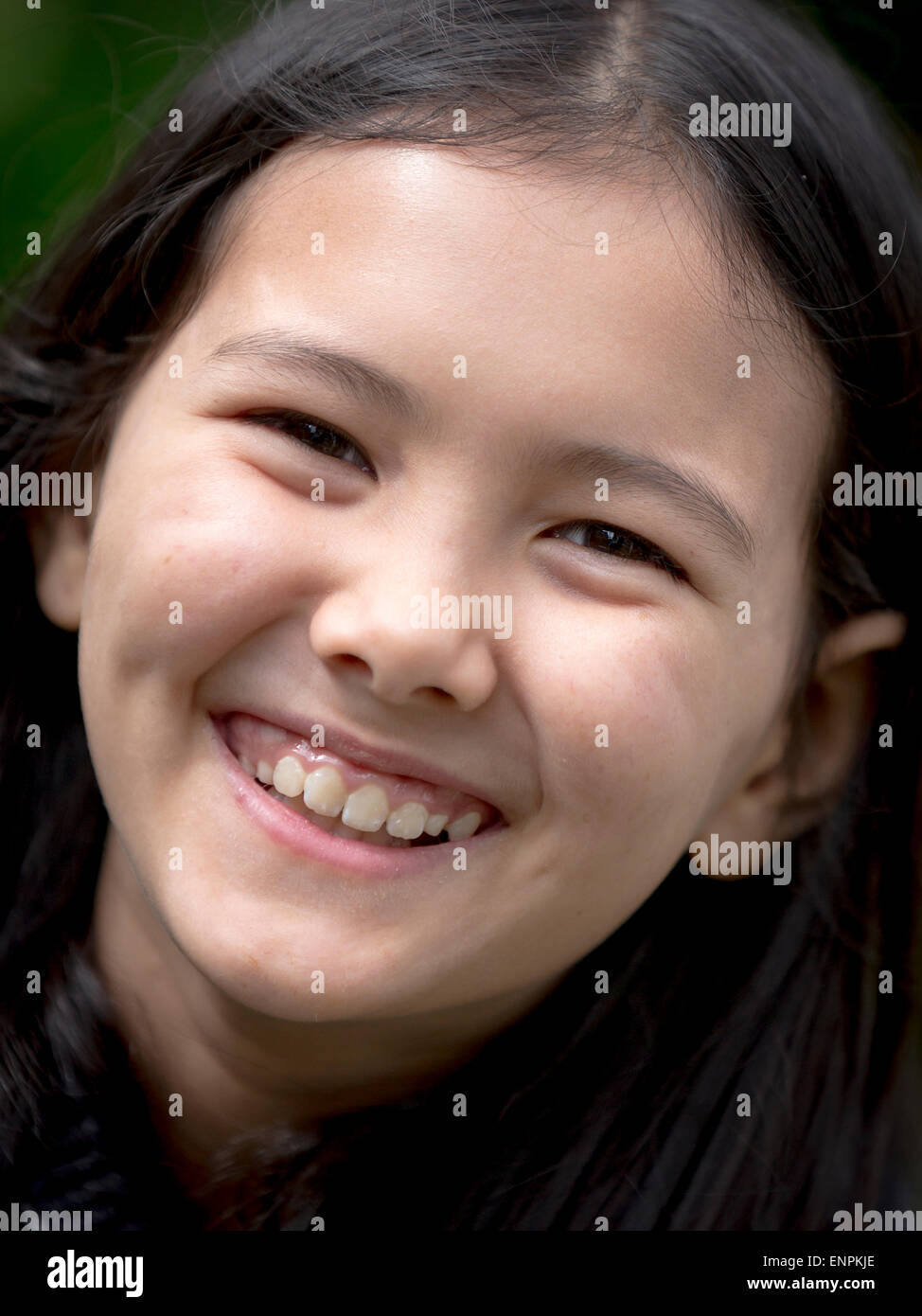 Portrait of a happy 9 year old Thai, English girl sitting in a garden Stock Photo