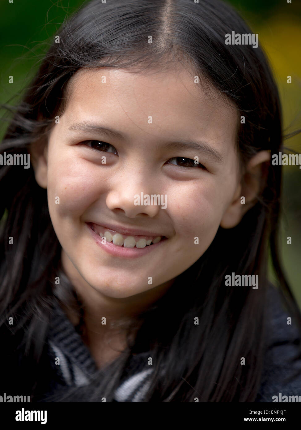 Portrait of a happy 9 year old Thai, English girl sitting in a garden Stock Photo