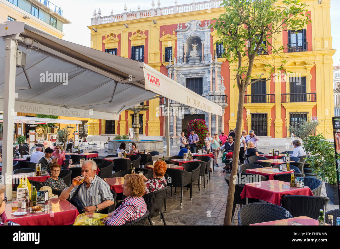 Malaga, Spain. Malaga, Spain. People sitting at a terrace by the Bishop's Palace (Palacio Episcopal) at Bishop Square (Plaza del Stock Photo