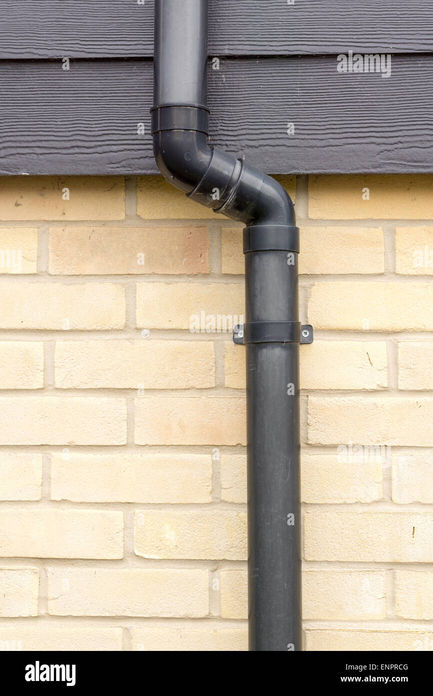 Close up of a black drainage pipe and clip on a brick wall Stock Photo