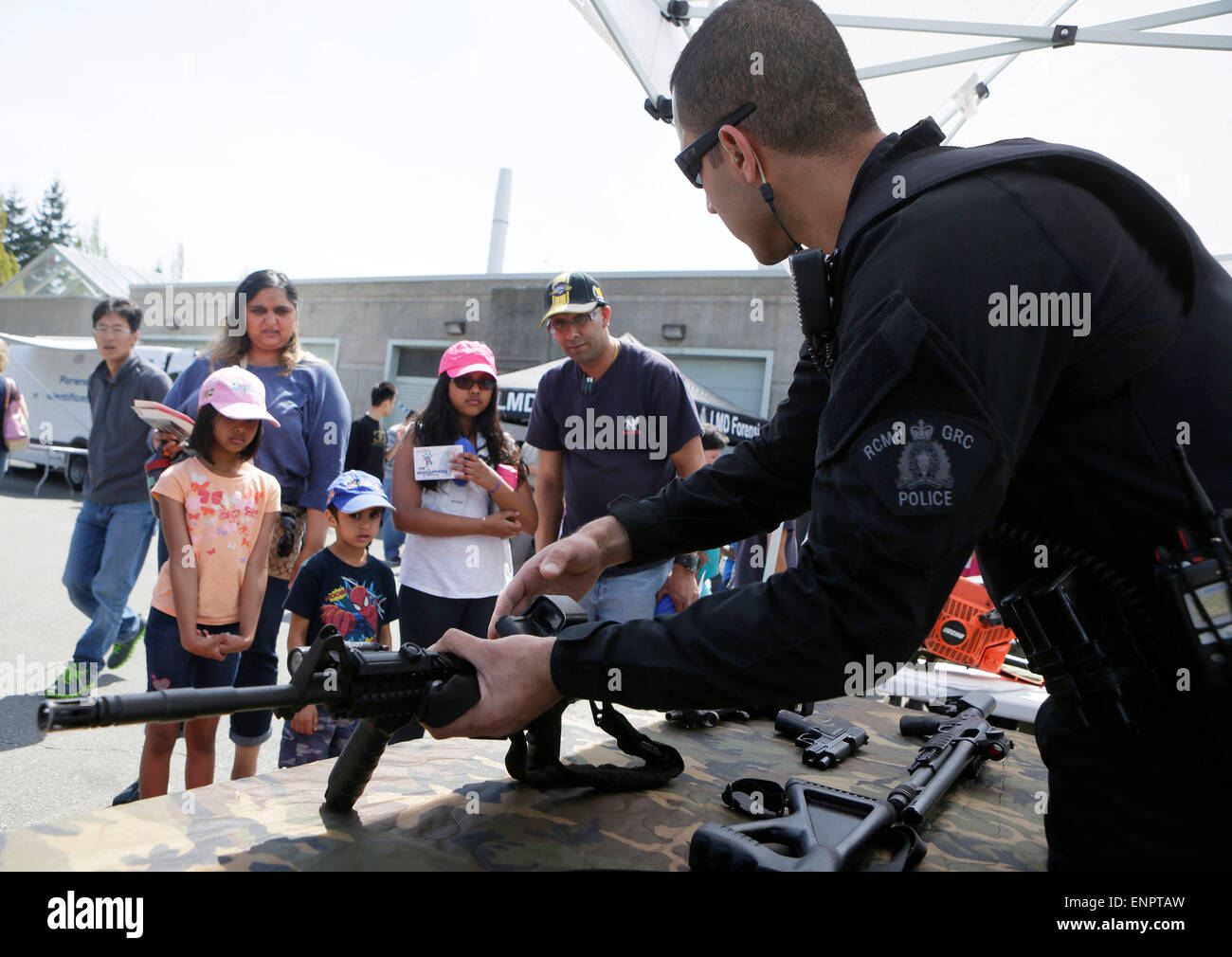 Surrey, Canada. 9th May, 2015. A policeman introduces weapons to visitors during an open day event in Surrey, Canada, May 9, 2015. The Surrey police on Saturday held the open day event for the National Police Week. Credit:  Liang Sen/Xinhua/Alamy Live News Stock Photo