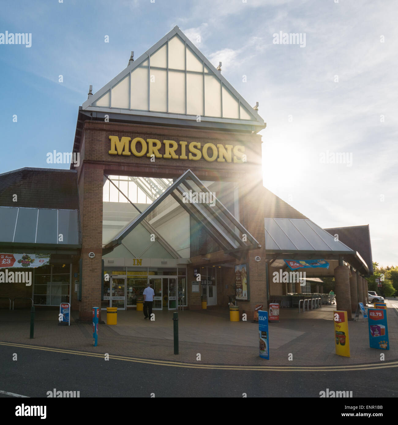 Morrisons supermarket entrance back lit by late sun Stock Photo