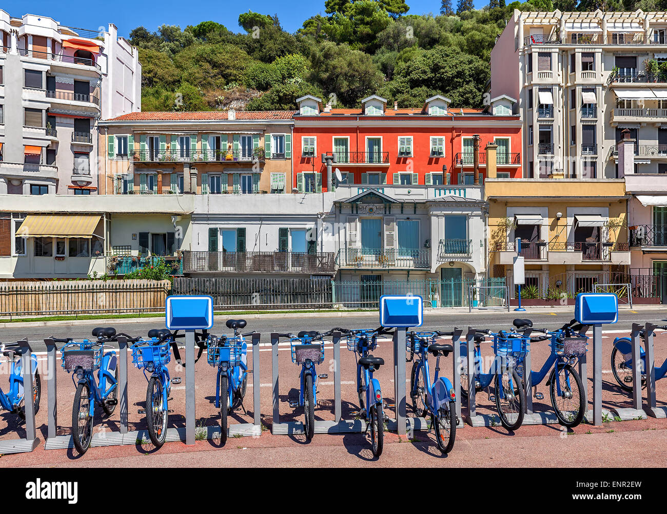 City bicycles at sharing station and colorful houses on background in city of Nice, France. Stock Photo