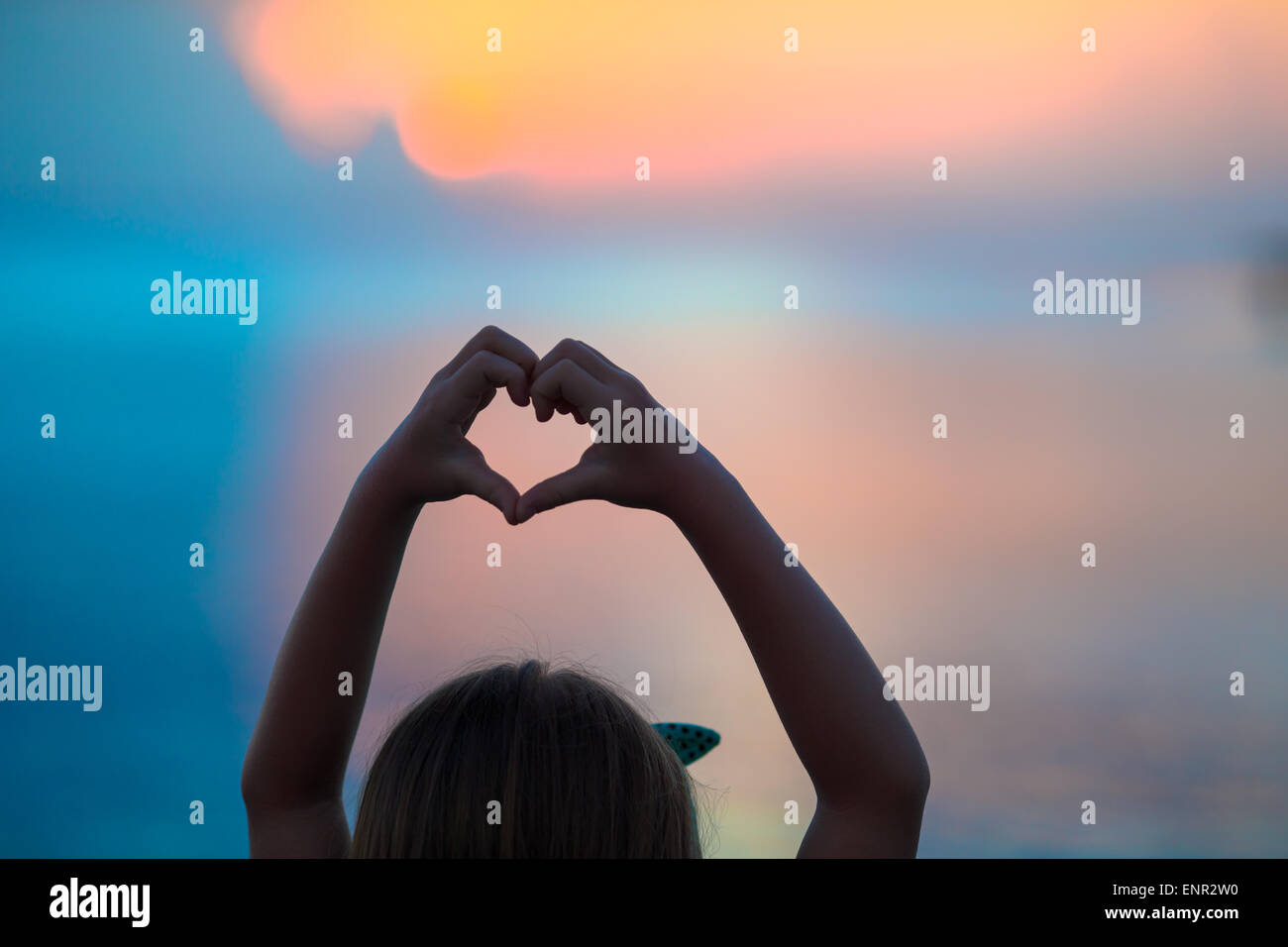 Silhouette of heart made by kids hand at sunset Stock Photo