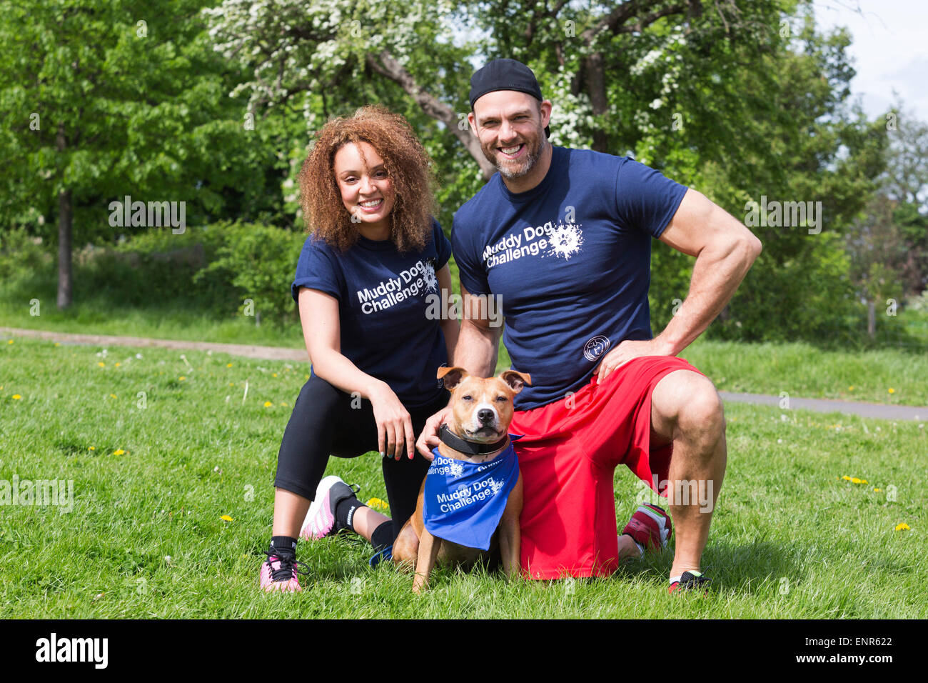 London, UK. 10 May 2015. Capital FM DJ Pandora poses with her fiance James Crossley (former Gladiator) and their dog Henry, a Staffie-cross. Battersea Dogs & Cats Home hosted its very first Muddy Dog Challenge giving owners the opportunity to test their fitness and tackle obstacles alongside their four-legged friends in Brockwell Park, South London. 191 dogs and 260 runners took part to raise funds for Battersea Dogs & Cats Home. Photo: Nick Savage/Alamy Live News. Stock Photo