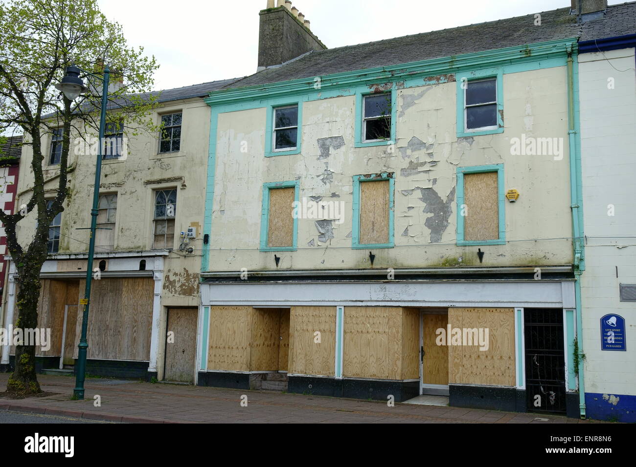 boarded up shops on egremont main street cumbria falling into disrepair with peeling paint and broken windows Stock Photo