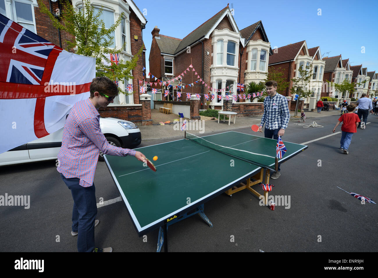 Two men play table tennis or ping pong in the street outside houses in