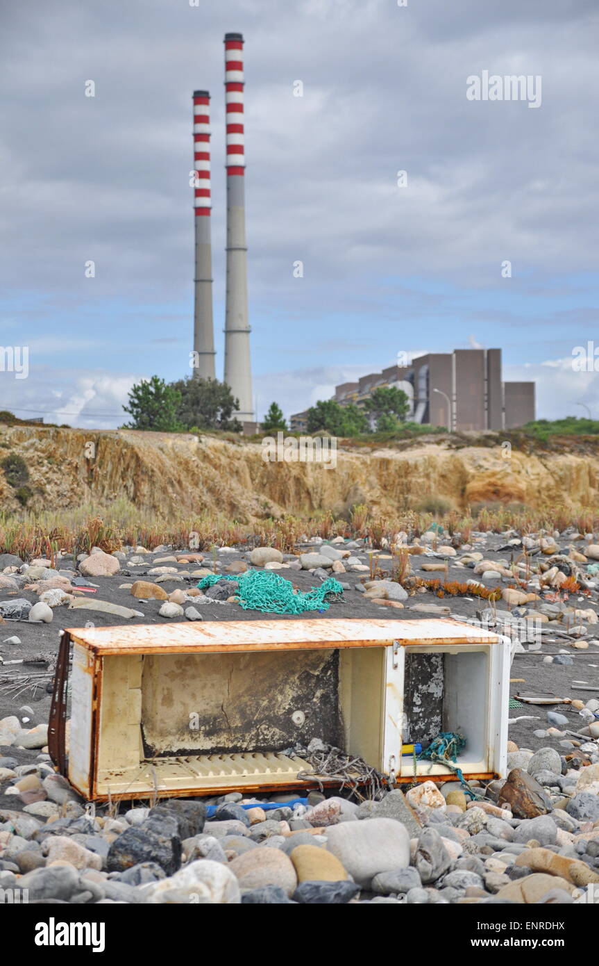 Trashed fridge on the seashore next to a factory Stock Photo