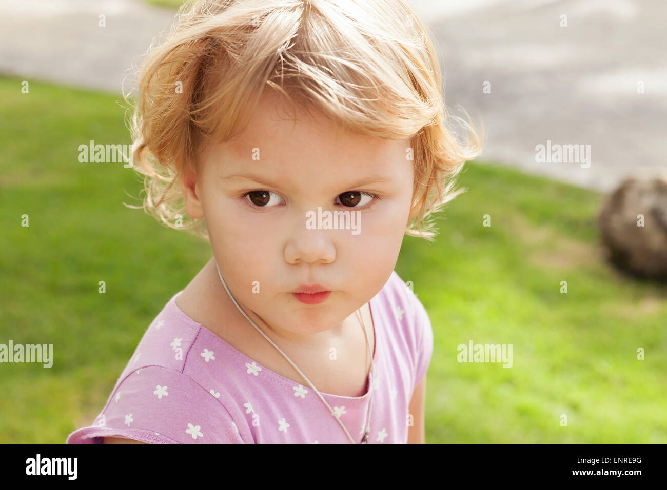 Outdoor closeup portrait of cute Caucasian blond baby girl in a park ...