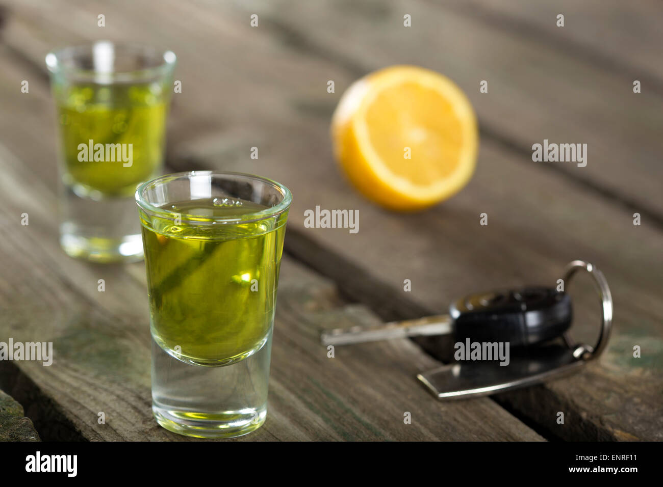 Car keys with Two shot glasses over wood background - drink drive concept Stock Photo