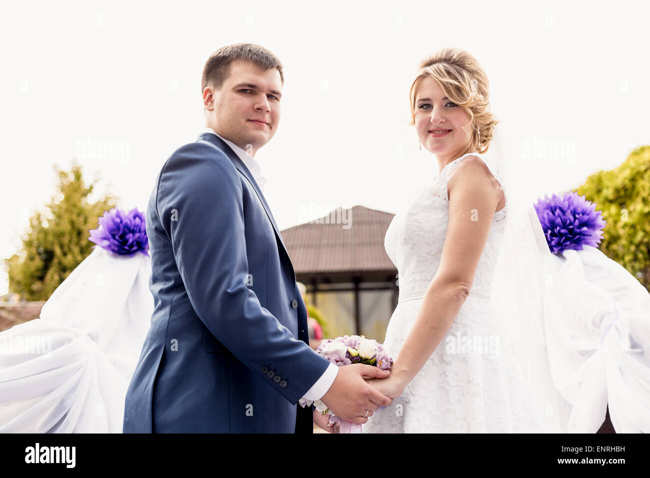 Portrait of happy bride and groom holding hands at park Stock Photo - Alamy