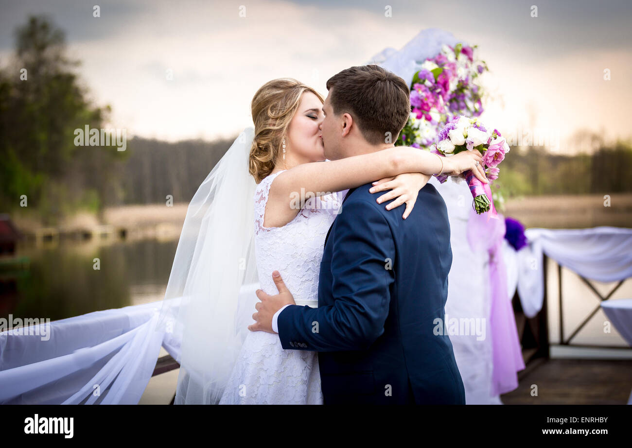 Portrait of happy bride and groom kissing on sunset at river Stock ...