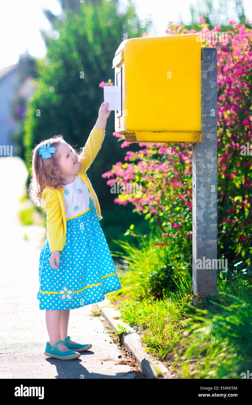 Little girl with an envelope at post office. Child sending letter. Kid