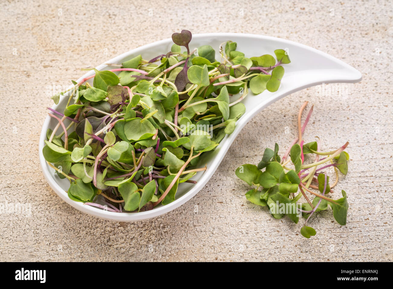 organic micro greens (kale, mustard, pea, herbs) on a ceramic teardrop shaped bowl against grunge bran wood Stock Photo