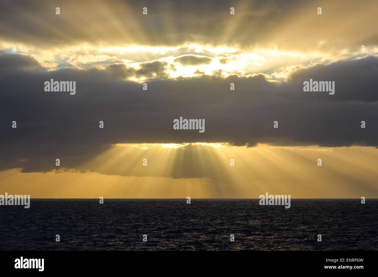 Yellow sunrays in the sky at sunrise while sailing in the Atlantic ocean Stock Photo